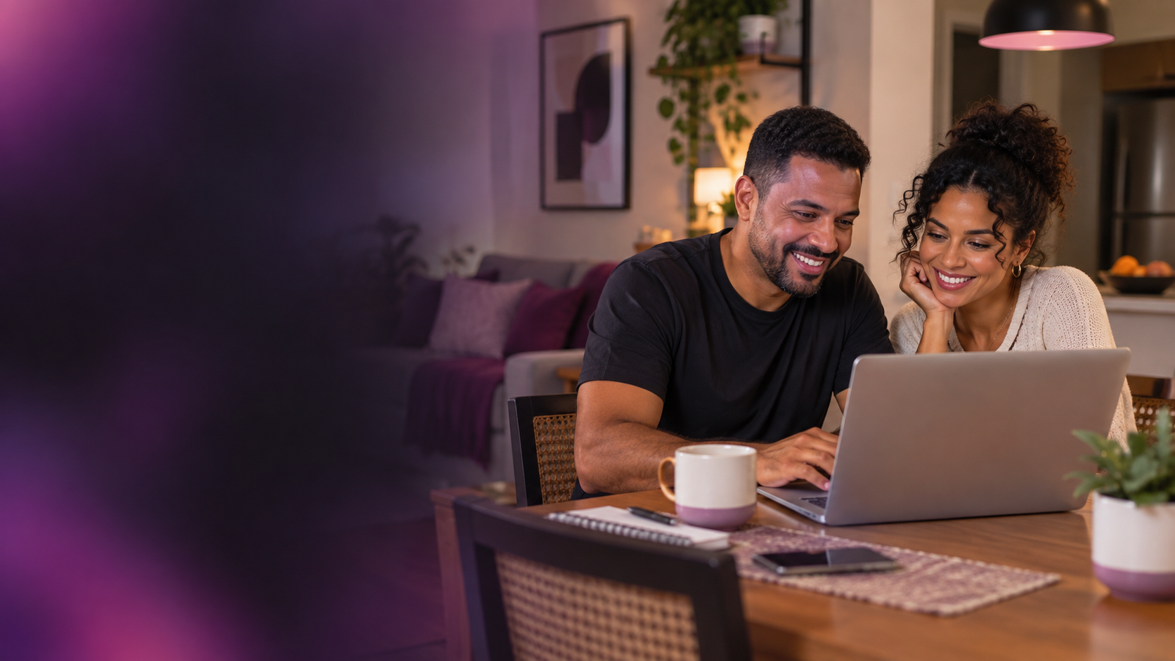 Casal sorrindo em casa, usando um notebook para organizar seus planos